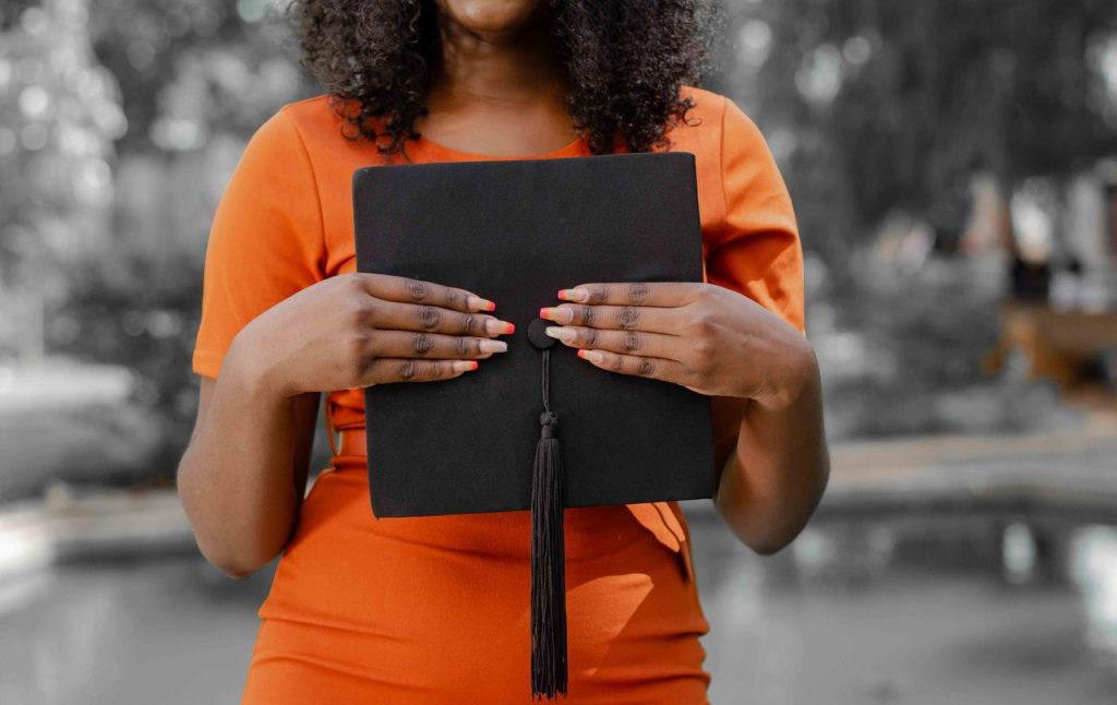 Young woman holding a black graduation cap, symbolizing academic achievement.