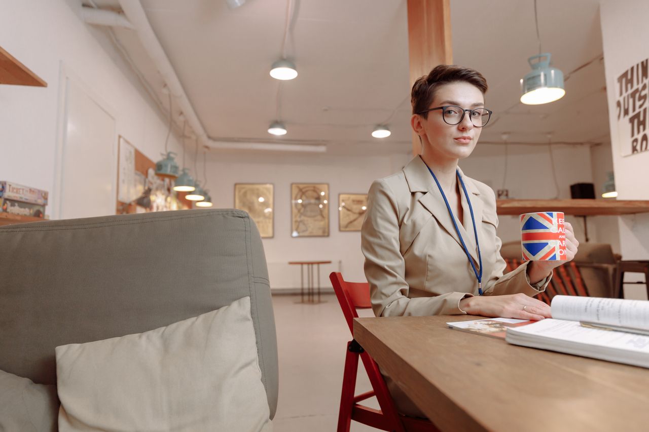 Businesswoman with Union Jack mug in a modern office setting.