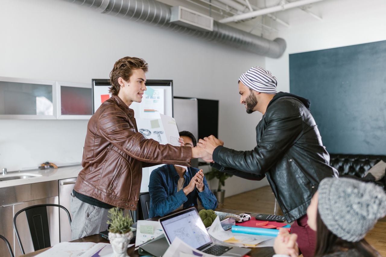 The Art of Drawing Readers In: Your attractive post title goes here Two men shaking hands in a modern office setting, symbolizing a successful business agreement.